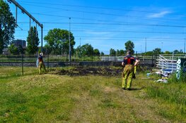 Brandweer blust brandend gras naast spoor Beverwijk